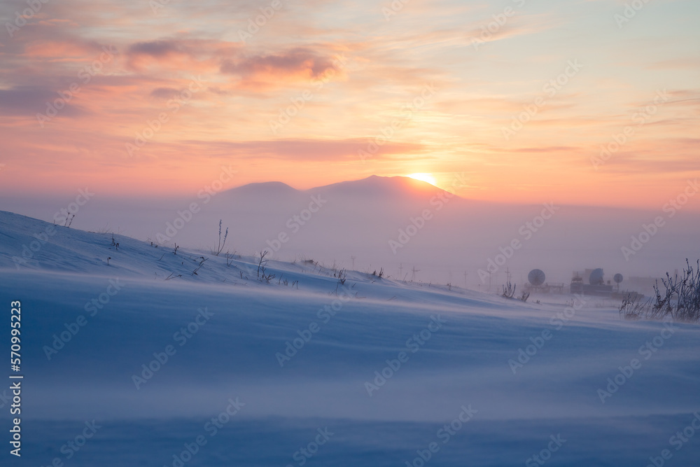Winter arctic landscape. Satellite dishes in the winter snow-covered tundra in the Arctic. Cold frosty and windy winter weather. Sunset over the tundra and mountains. Chukotka, Siberia, Russia, Arctic