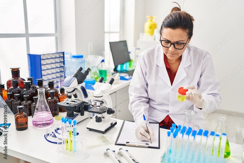 Middle age hispanic woman wearing scientist uniform analysing urine test at laboratory Middle age hispanic woman wearing scientist uniform analysing urine test at laboratory