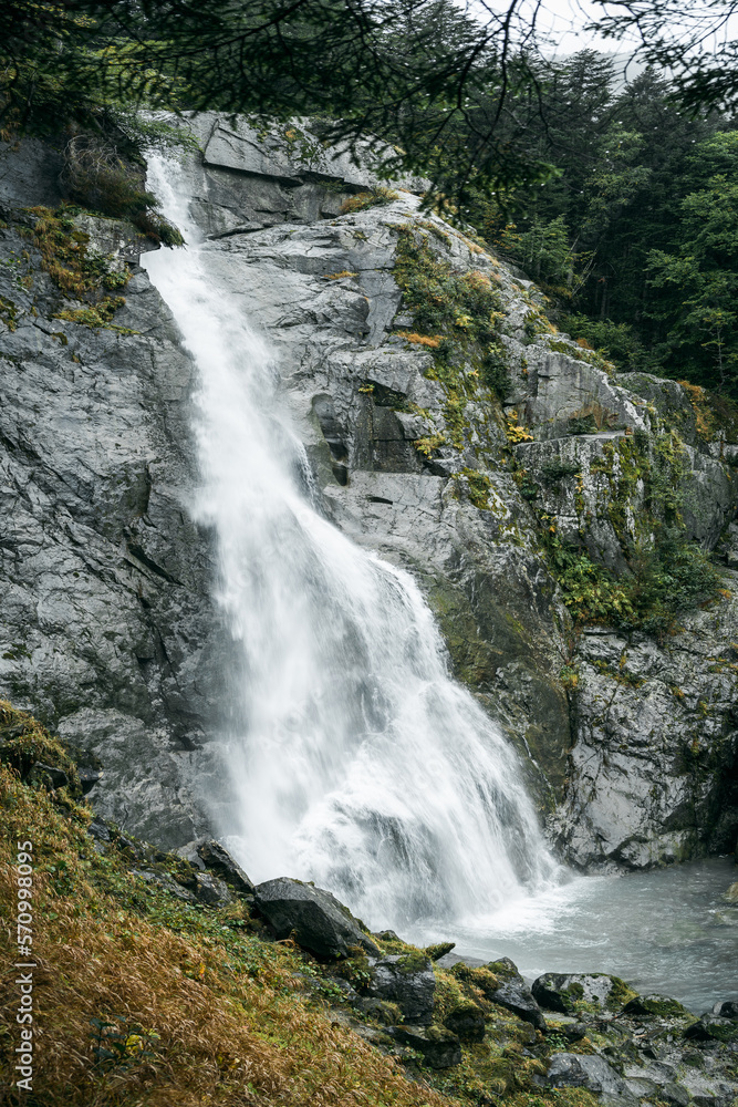 Fototapeta premium View of a waterfall during a rainy and foggy autumnal day in the forest of Val di Genova, Trentino Alto Adige, Northern Italy