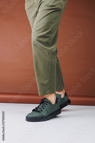 Summer shoes. Close-up of male legs in green pants and green casual sneakers. Summer leather men's shoes