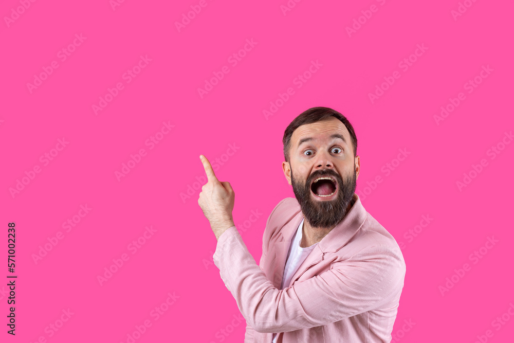 A man dressed in a pink jacket indicates the direction on a pink isolated background. A man dressed in a pink jacket indicates the direction on a pink isolated background.