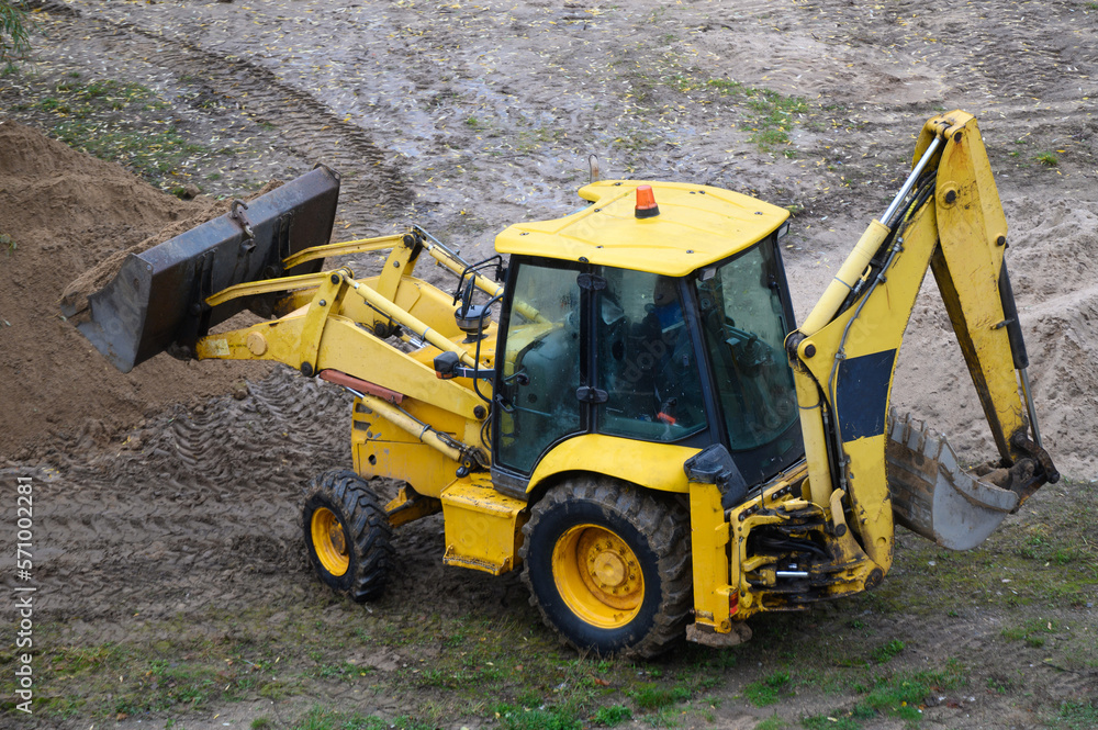 Yellow tractor-based bulldozer excavator at a construction site.Earthmoving machine. Leveling the soil for the construction of a new house. Yellow tractor-based bulldozer excavator at a construction site.Earthmoving machine. Leveling the soil for the construction of a new house.