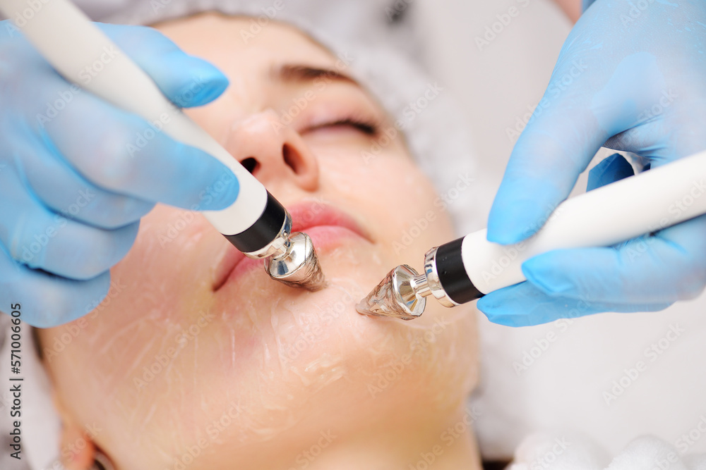 cosmetologist conducts microcurrent facial therapy for a young woman using a device in a beauty salon. Hardware cosmetology, skin care, rejuvenation, regeneration. cosmetologist conducts microcurrent facial therapy for a young woman using a device in a beauty salon. Hardware cosmetology, skin care, rejuvenation, regeneration.