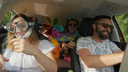A crazy funny family with children traveling in a car. Woman in diving mask with a snorkel, everyone is having fun and dancing, enjoying their vacation, freedom