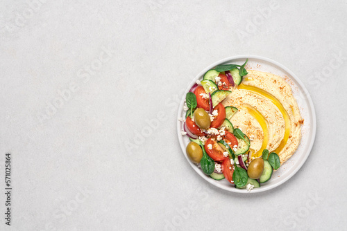 Hummus salad in plate on light background with copy space. Healthy food. Dip plate appetizer with greek salad