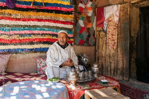 Elderly Berber man sitting on the terrace of his house preparing a tea. Traditional arabic hospitality.