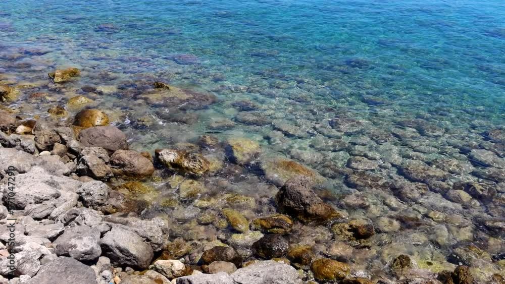 Sunny day by the sea, shoreline with stones and calm water. Rocks and ocean, video from outdoor trip. Waves on the water close to the shore. Sunny day by the sea, shoreline with stones and calm water. Rocks and ocean, video from outdoor trip. Waves on the water close to the shore.