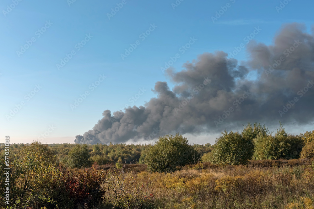 A large black column of thick smoke is visible on the horizon