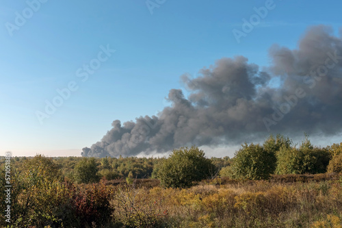 A large black column of thick smoke is visible on the horizon