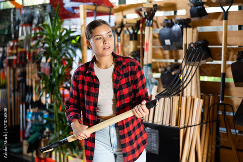 Valokuvatapetti Female farmer choosing pitchfork in a gardening store