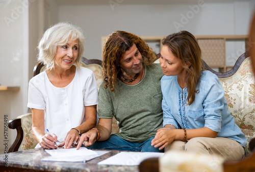 Mature woman at table in home room filling up documents with family