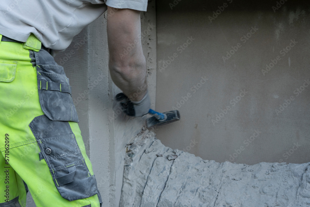 Man Demolishing Concrete Wall for Window Hole Creation.