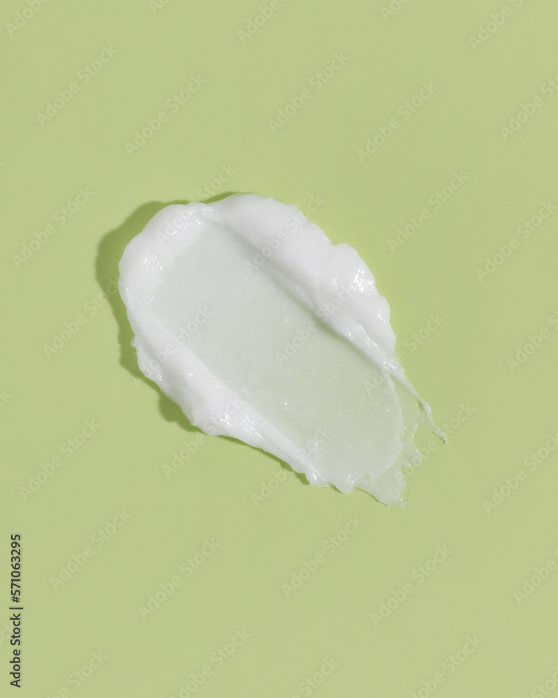 White beauty cream smear smudge on green background. Cosmetic skincare product texture. Face cream, body lotion swipe swatch White beauty cream smear smudge on green background. Cosmetic skincare product texture. Face cream, body lotion swipe swatch