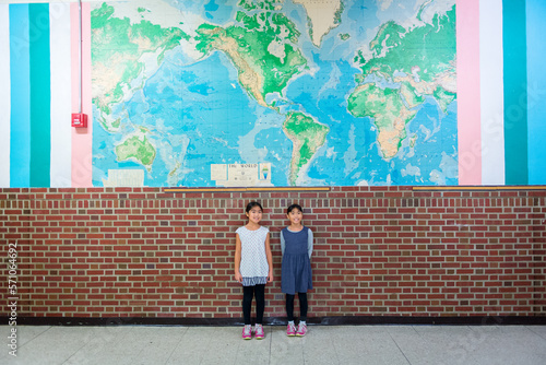 Wallpaper Mural Two young asian elementary studunts standing in front of large world map Torontodigital.ca