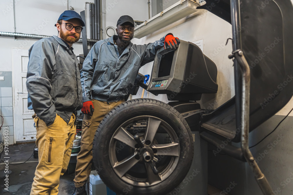 multiracial mechanics posing for a picture in a car repair shop, medium full shot. High quality photo