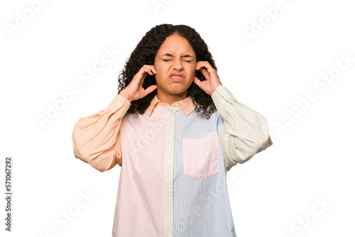 Young african american curly woman isolated covering ears with fingers, stressed and desperate by a loudly ambient.