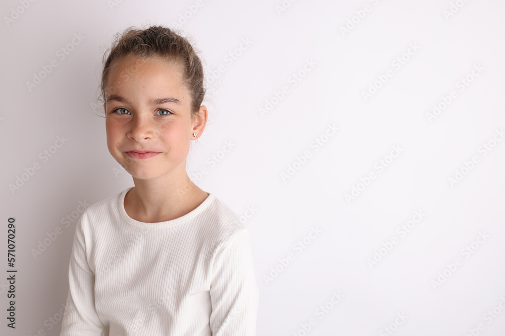 Little emotional teen girl in white shirt 11, 12 years old on an isolated white background. Children's studio portrait. Place text, to copy space for inscription, advertising children's goods. Little emotional teen girl in white shirt 11, 12 years old on an isolated white background. Children's studio portrait. Place text, to copy space for inscription, advertising children's goods.