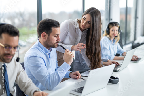 Canvas-taulu Young female supervisor assisting helpdesk operator at office in call center