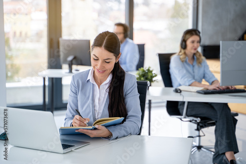 Portrait of beautiful business woman taking notes at office.