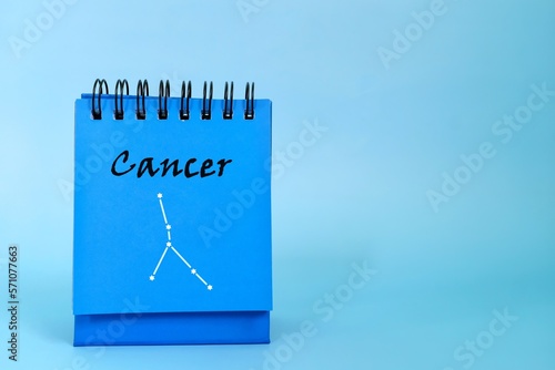 Cancer zodiac sign on blue desk calendar notepad. Horoscope and astrology concept.