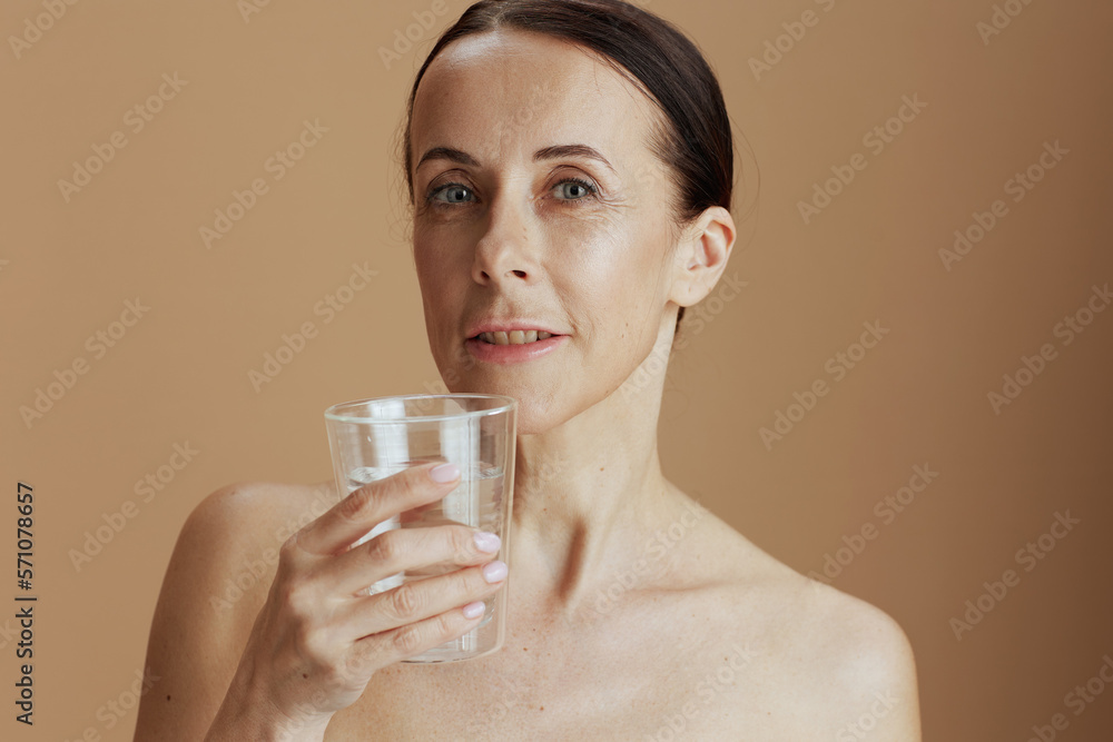 modern woman with glass of water isolated on beige background modern woman with glass of water isolated on beige background