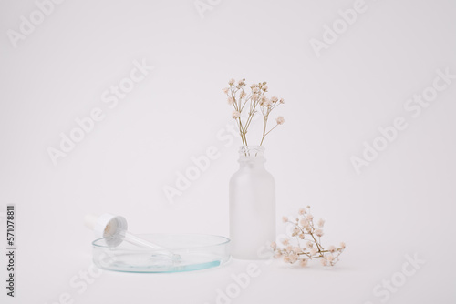 Glass skincare bottle with flower top view for self-care and wellness concept.