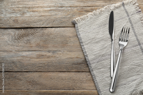 Fork, knife and napkin on wooden table, top view with space for text. Stylish shiny cutlery set photo