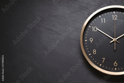 Stylish round clock on black table, top view with space for text. Interior element