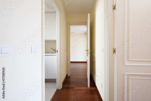 Corridor of a house with red wooden floors and white lacquered wooden access doors to different rooms