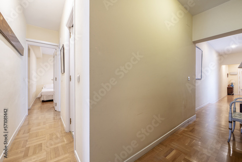 Hallway of a house with oak checkerboard wooden floors and white wooden doors leading to other rooms