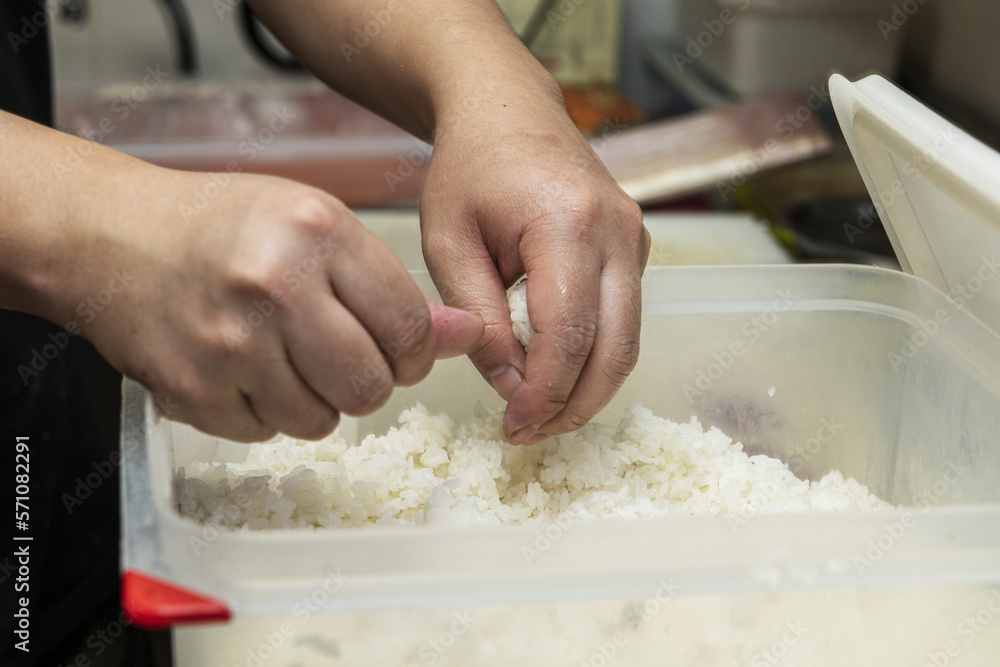 A Japanese chef putting the finishing touches on white rice balls to prepare sushi A Japanese chef putting the finishing touches on white rice balls to prepare sushi