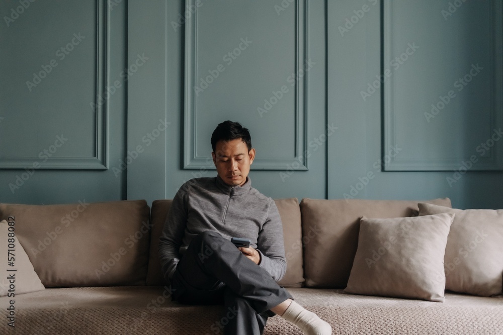 Asian man in fleece sitting in the living room in cold weather. Asian man in fleece sitting in the living room in cold weather.