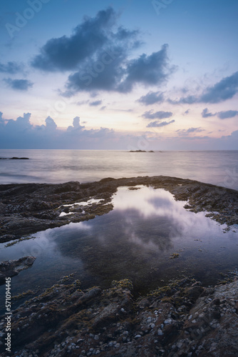 Fototapeta Naklejka Na Ścianę i Meble -  vertical photo of a sea sunset and rocks. The dramatic evening sky is reflected in the seawater coast nature of thailand phuket kaolak