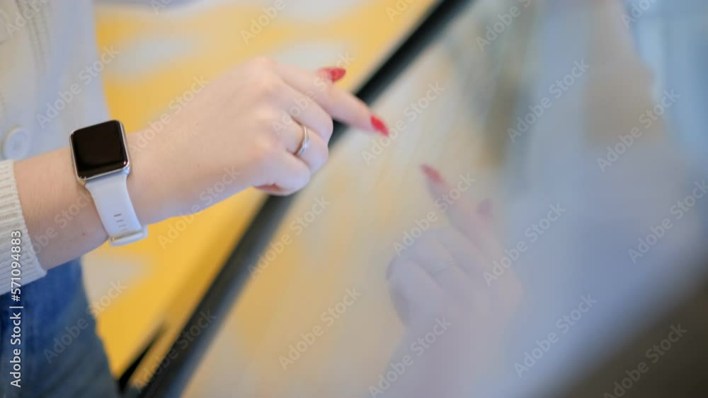 Close-up. A young girl using a touch terminal in a shopping mall.The girl uses a touch terminal to search for the right store.The concept of people and technologies. 4K Close-up. A young girl using a touch terminal in a shopping mall.The girl uses a touch terminal to search for the right store.The concept of people and technologies. 4K