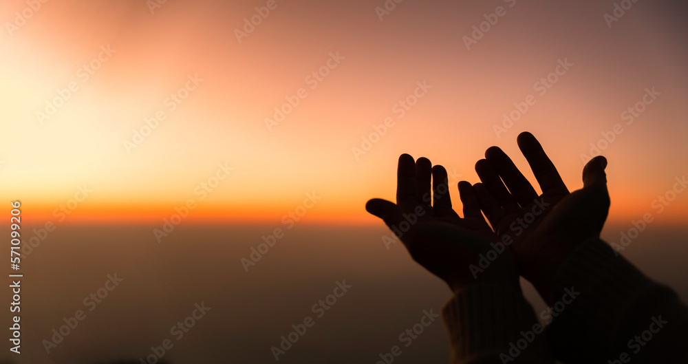 Silhouette of woman hands praying for worship God at sky background. Christians pray to jesus christ for calmness. In morning people got to a quiet place and prayed. Banner with copy space.