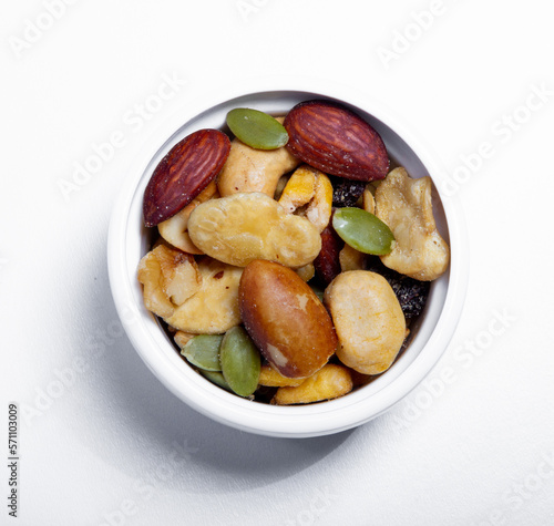 Nut mix in small white plate. Nuts - pecans, macadamias, Brazil nuts, walnuts, almonds, hazelnuts, pistachios, cashews, peanuts. Upper view.