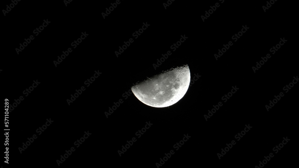 Obraz premium Moon, close-up shot. A half moon. Lunar context. Moonlight. A bright moon. Moon craters. Moon in the sky. 
