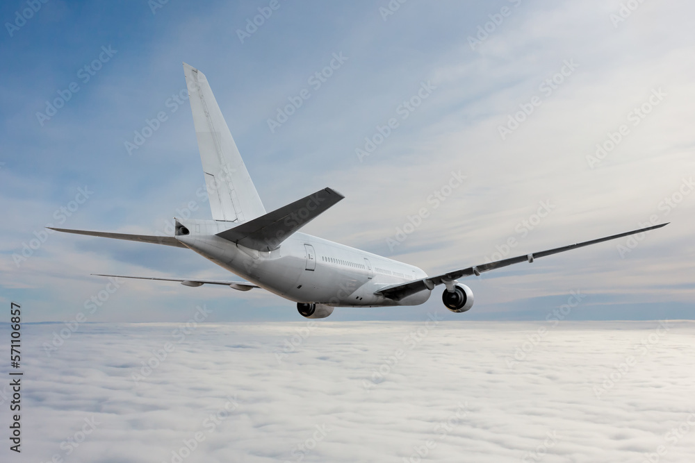 Fototapeta premium White wide body passenger airplane flying in the air above the clouds