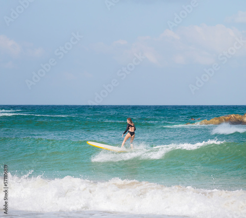 A young woman is surfing on a sunny windy day