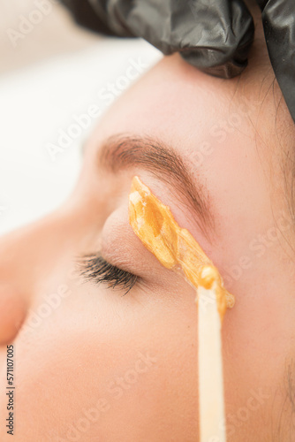 Young woman undergoing eyebrow correction procedure in beauty salon, closeup. Dying eyebrows whith brush