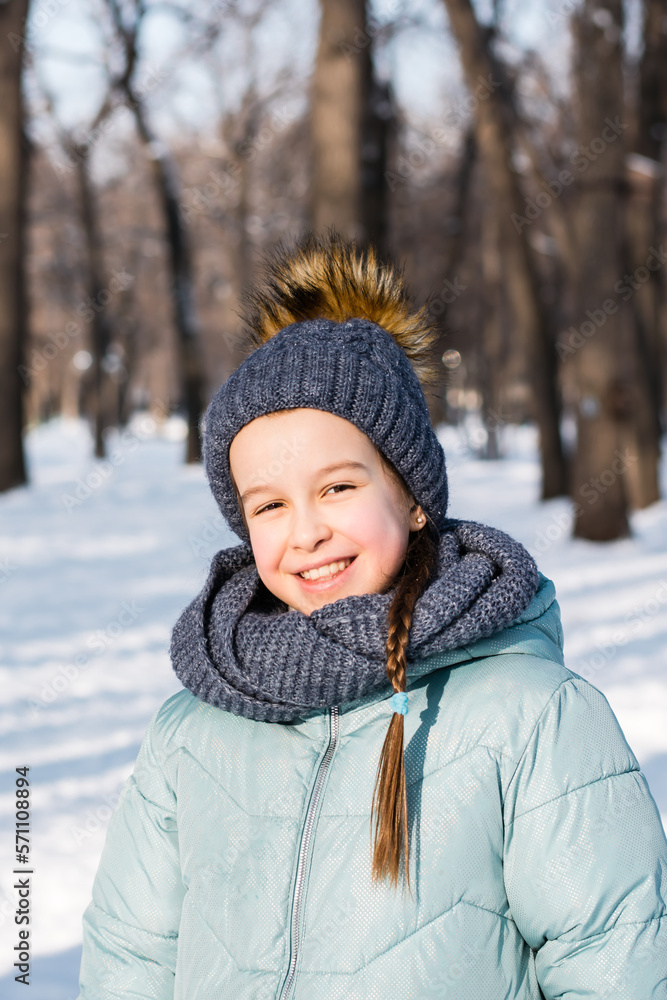 Smiling girl in warm clothes in a winter park on a frosty sunny day. Outside walks. Smiling girl in warm clothes in a winter park on a frosty sunny day. Outside walks.