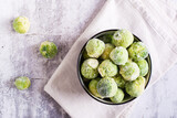 Frozen Brussels sprouts in a bowl on a gray background. Vegetarian food. Top view. Closeup