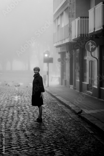 Obraz na płótnie A woman on a deserted street in the thick fall morning fog. Black and white photo. w salonie