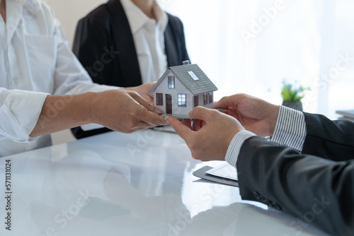 Young Asian real estate agent, and insurance salesman handing over a sample house to a client after signing the sale at the office.