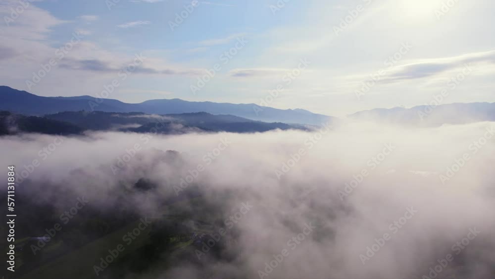 Aerial flight through low clouds on beautiful morning. Blue mountains in distance. Aerial flight through low clouds on beautiful morning. Blue mountains in distance.