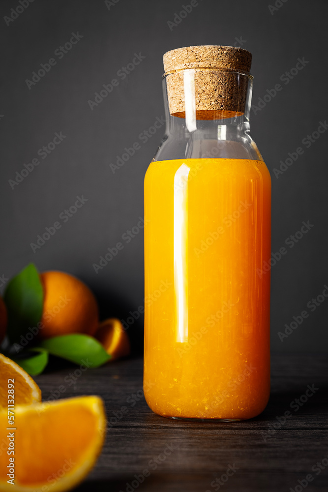 Orange juice in glass and fresh cut orange fruits on dark wooden background Orange juice in glass and fresh cut orange fruits on dark wooden background