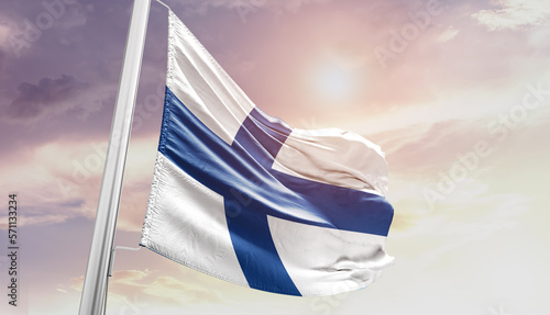 Waving Flag of Finland in Blue Sky. The symbol of the state on wavy cotton fabric.
