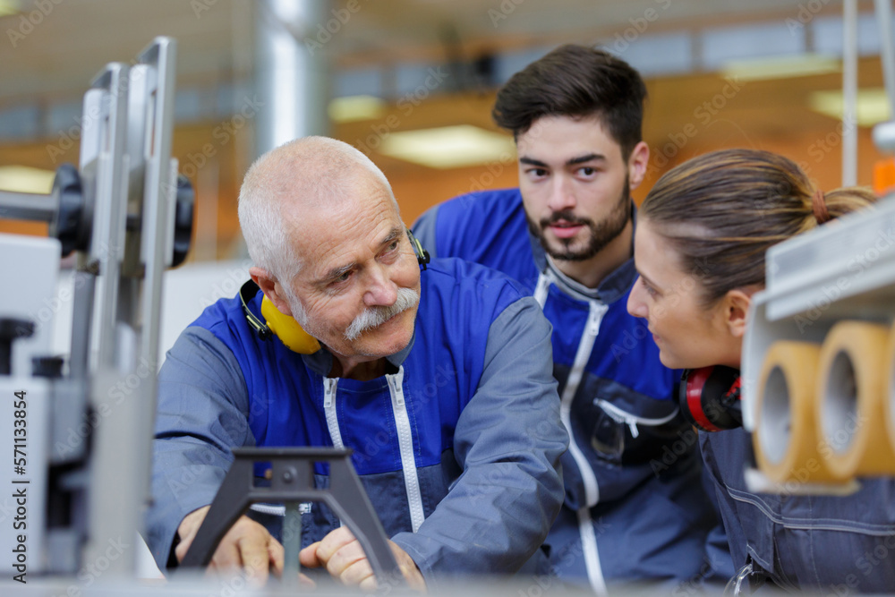 engineer and apprentice working on machine in factory engineer and apprentice working on machine in factory