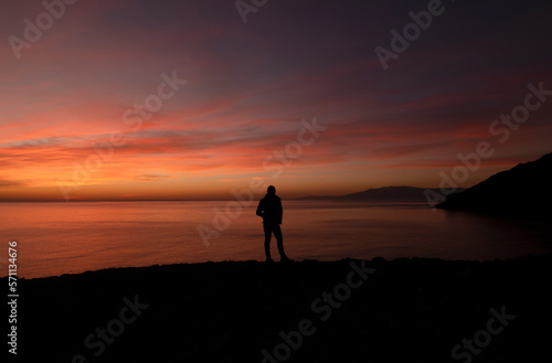Silhouette of adult man looking at sea view during sunset