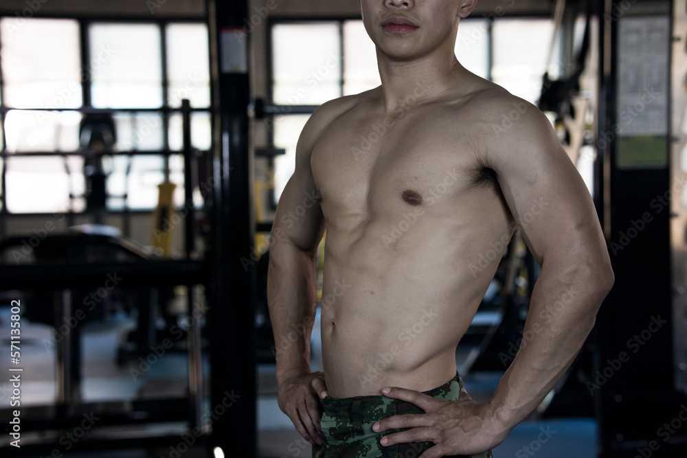Sexy body of muscular young Asian man in gym. Concept of health care, exercise fitness, Strong muscle mass, body enhancement, fat reduction for men's health supplement product presentation.